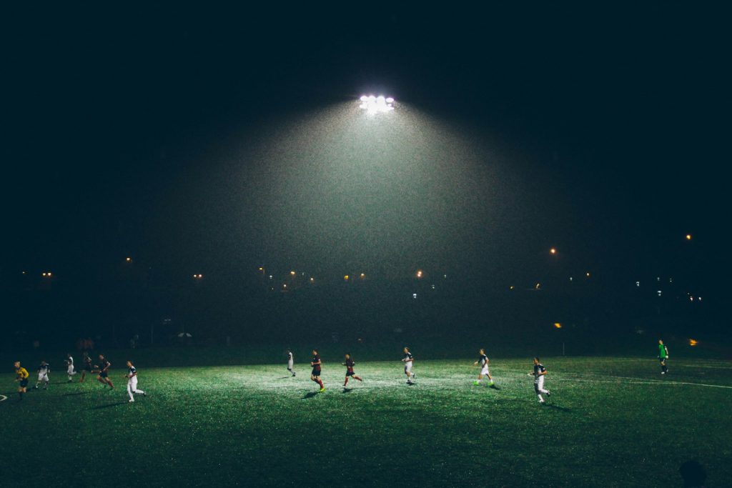 A goalkeeper diving to save a shot in a stadium with floodlights