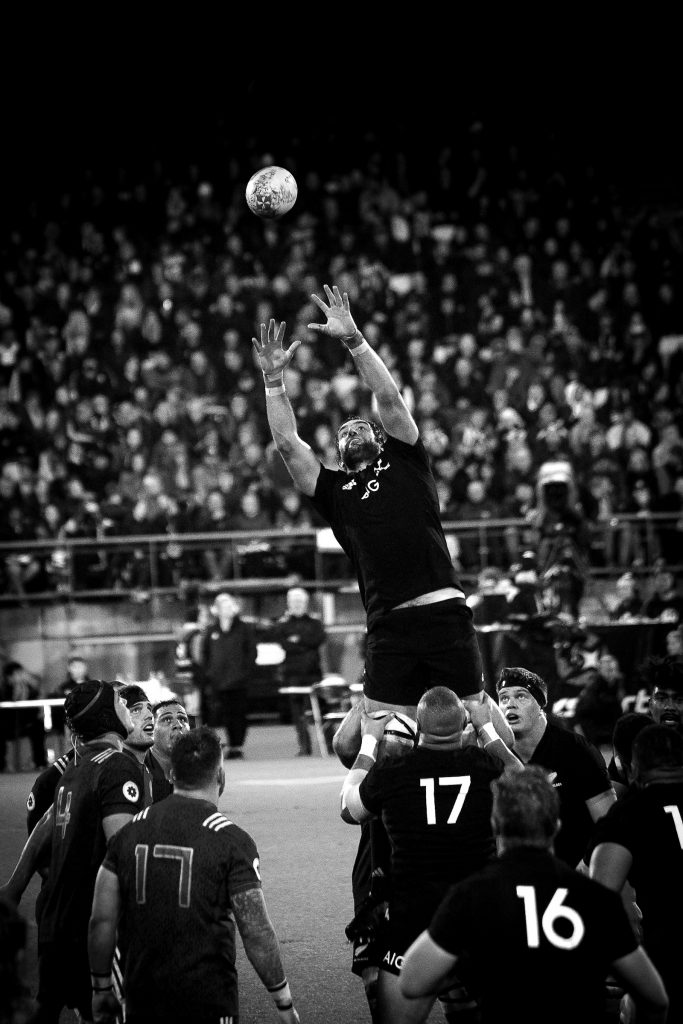 A grayscale photo of an NFL player catching a football mid-flight.