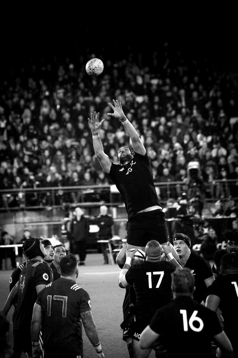 A grayscale photo of an NFL player catching a football mid-flight.