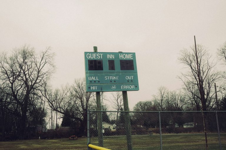 An outdoor baseball scoreboard with trees and fence behind it, used to illustrate how some sports metrics outlast the eras that produced them.