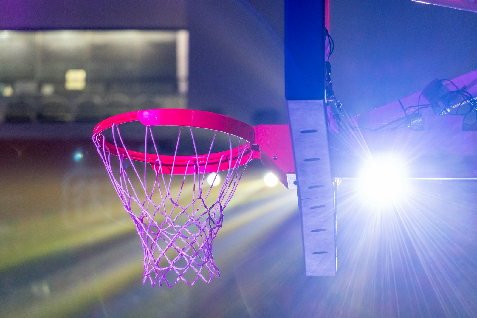 A basketball hoop dramatically lit by spotlight, used to illustrate how the NBA Round 1 spotlight tends to reveal which regular-season teams were carrying real depth and which were carrying mirages.