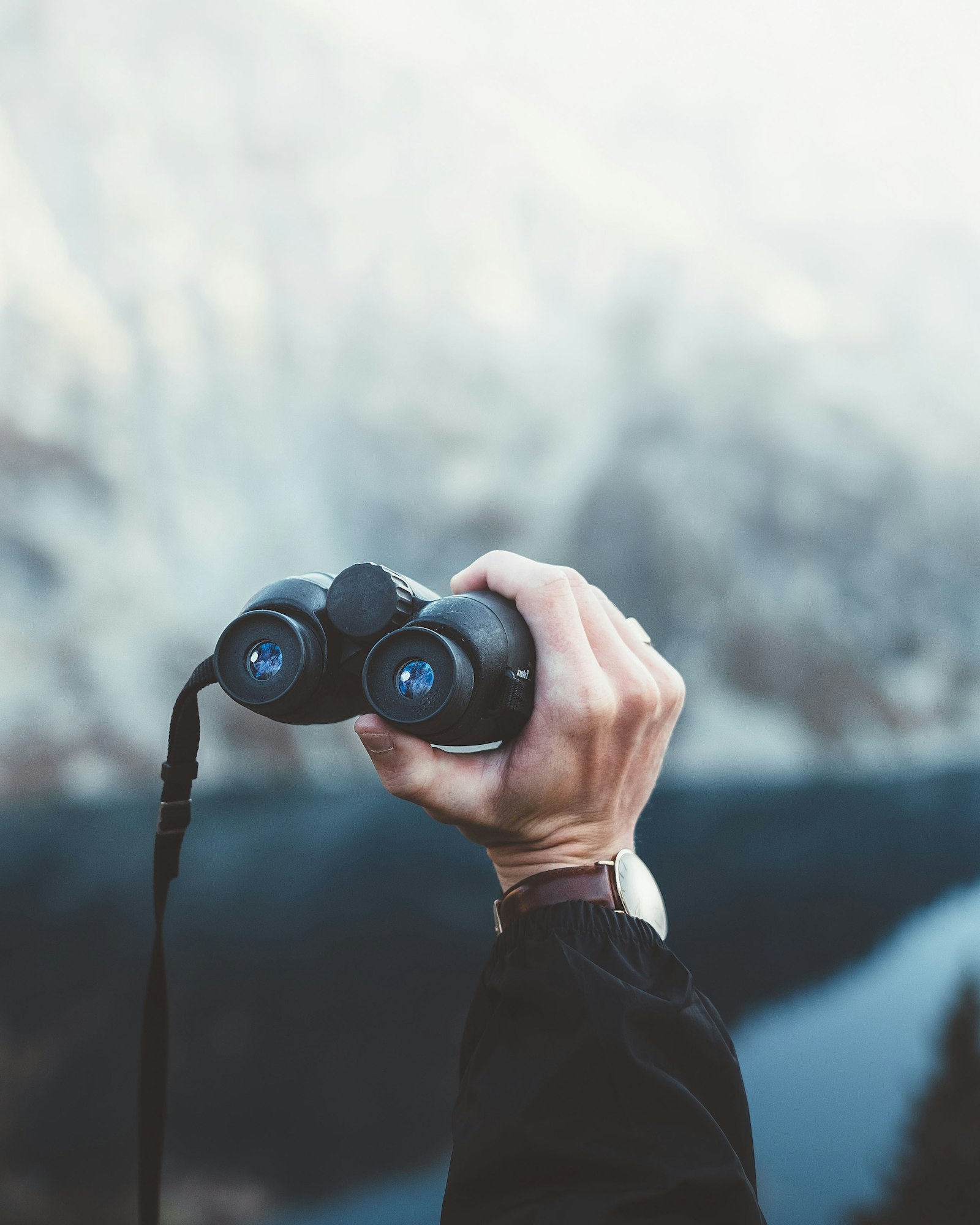 A person holding binoculars while observing, used to illustrate the qualitative observation tradition the "eye test" represents in sports analysis.