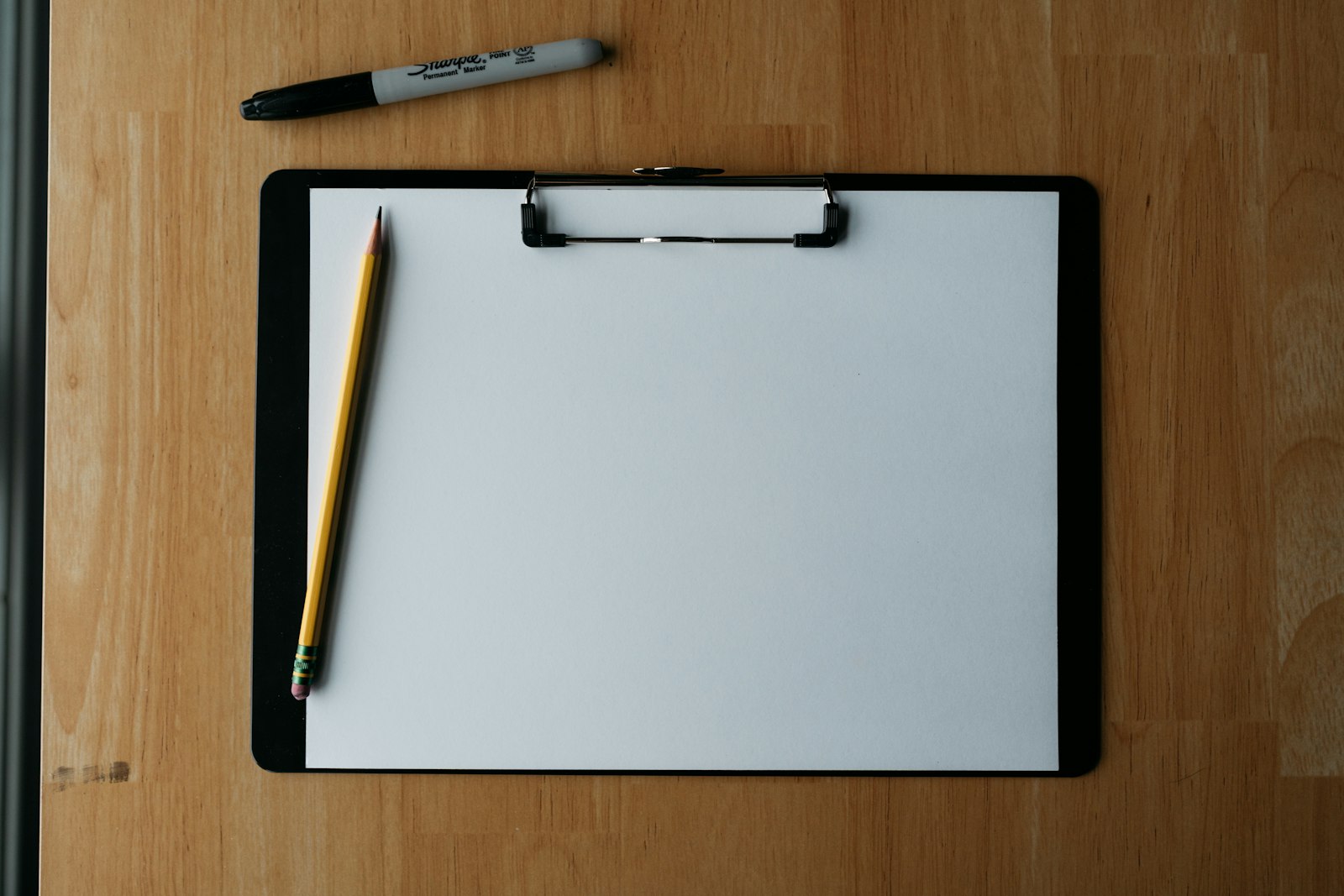 Clipboard with pencil and pen on a wooden surface, used to illustrate pre-Draft scouting analytics for AJ Dybantsa.