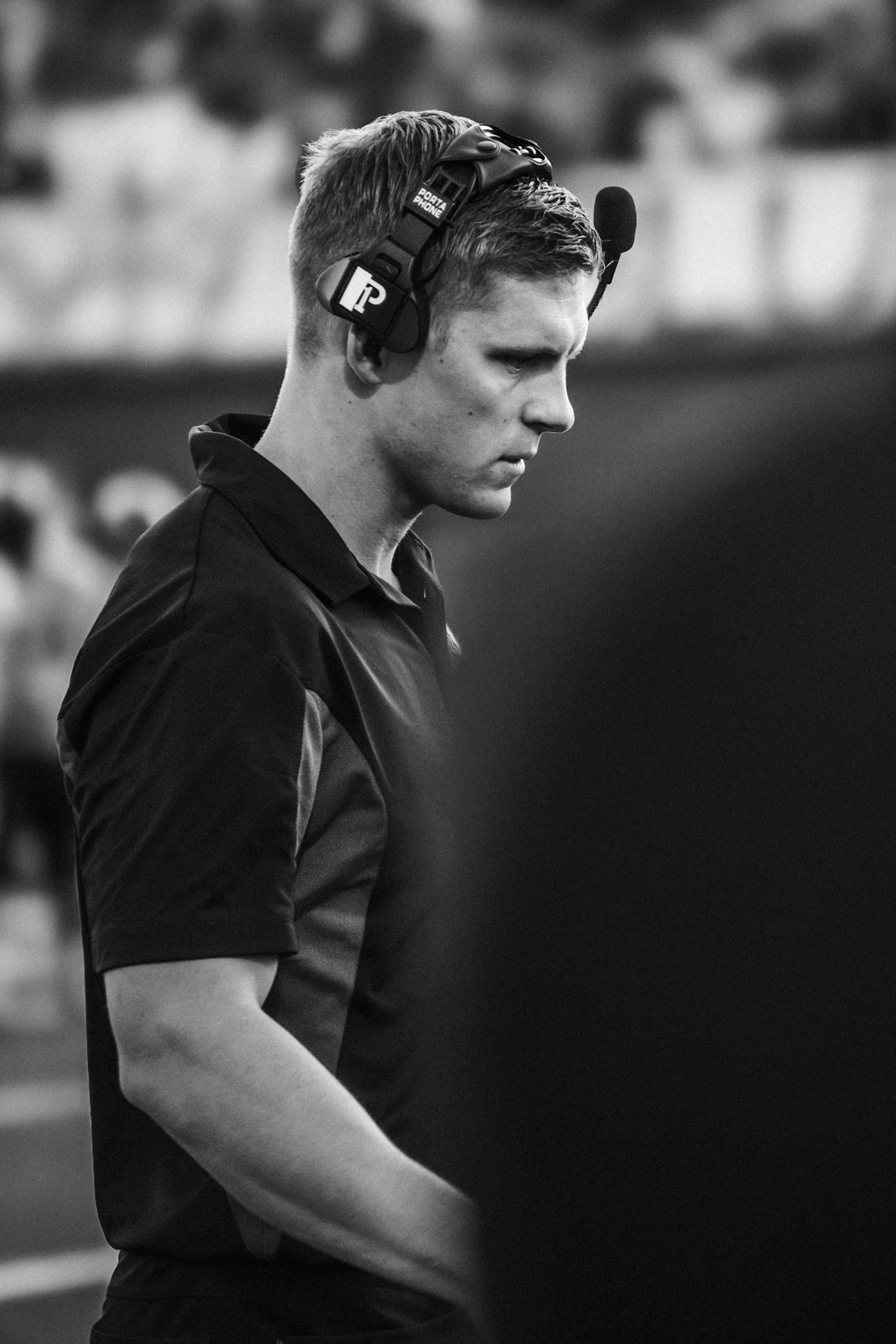 A football coach wearing a headset on the field, used to illustrate the staff-level evaluation that complements returning production in CFB projection.