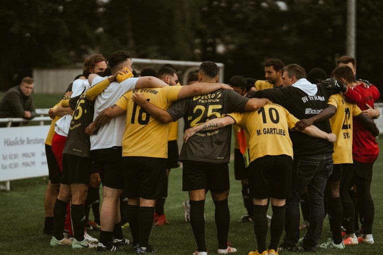 A group of soccer players huddle together on the field for team strategy.