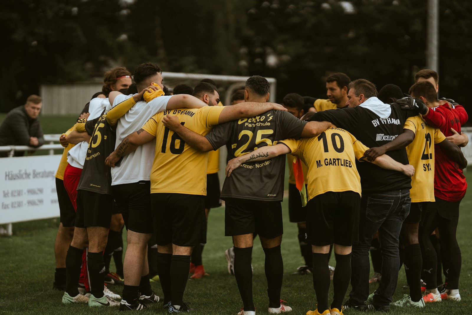 A group of soccer players huddle together on the field for team strategy.