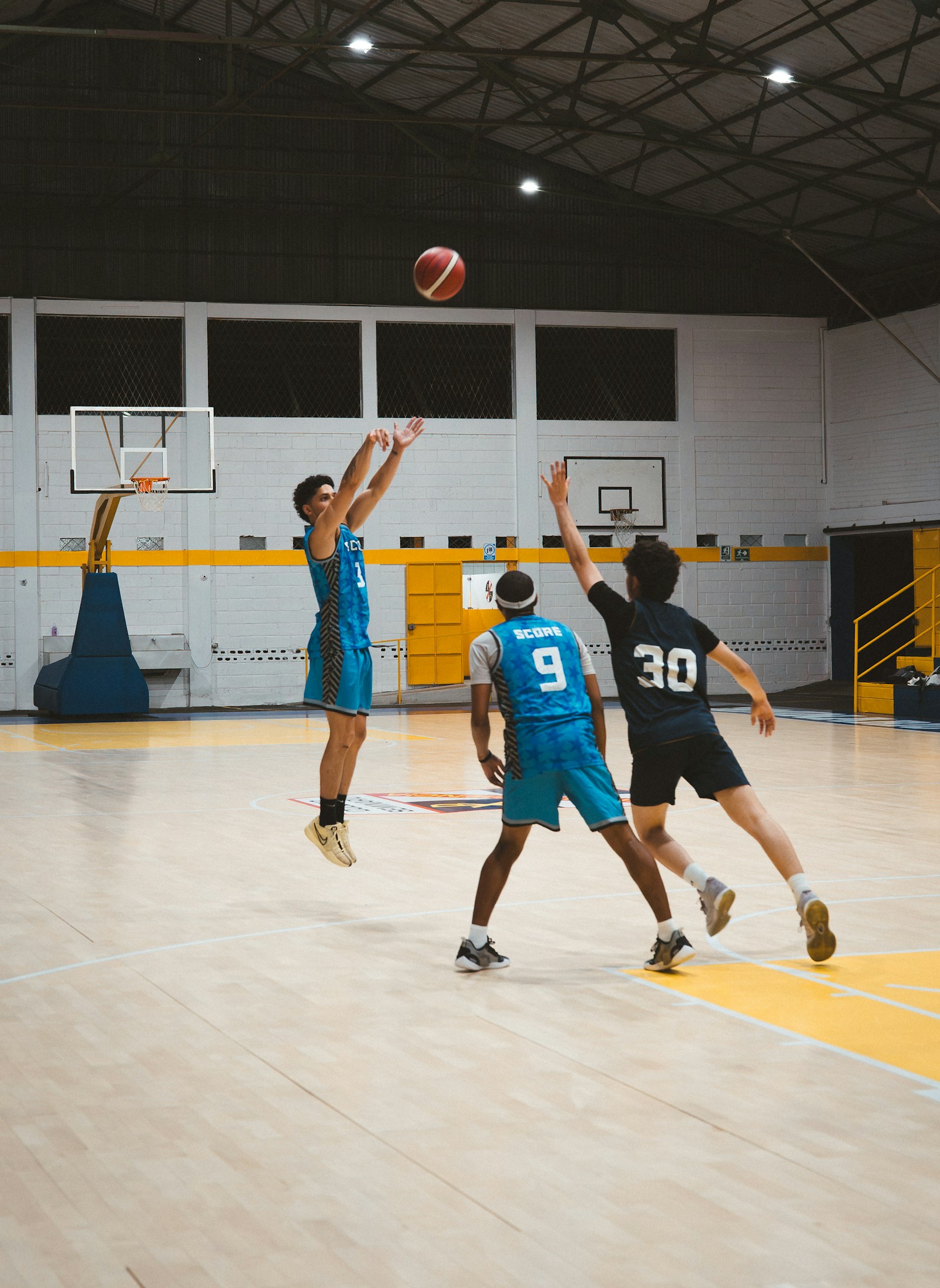 Three basketball players on a court during a competitive game.