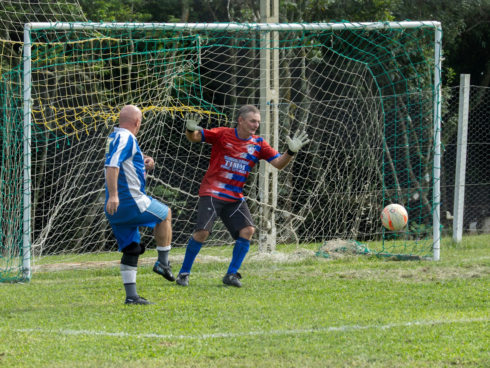 A soccer goalkeeper saves a soccer ball near the goal.