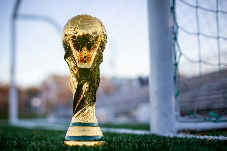 A golden soccer trophy sitting on top of a soccer field.