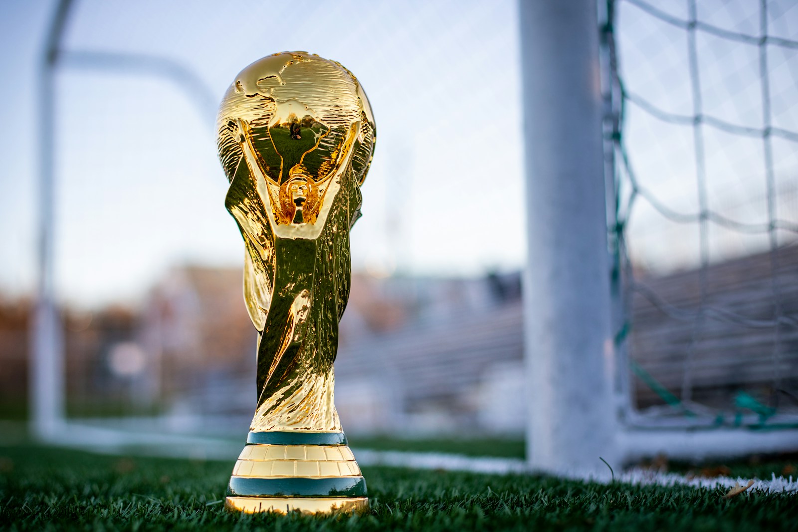 A golden soccer trophy sitting on top of a soccer field.