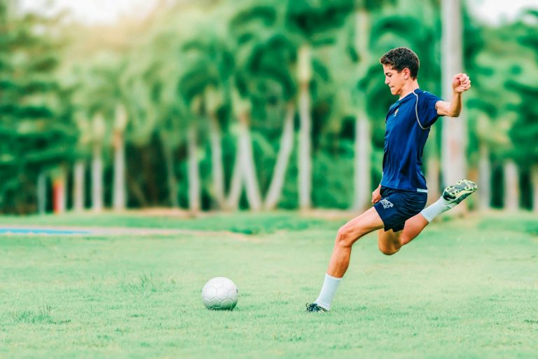 A soccer player kicking a ball on a grass field, used to illustrate the kind of player evaluation analytics that drives January transfer window decisions.