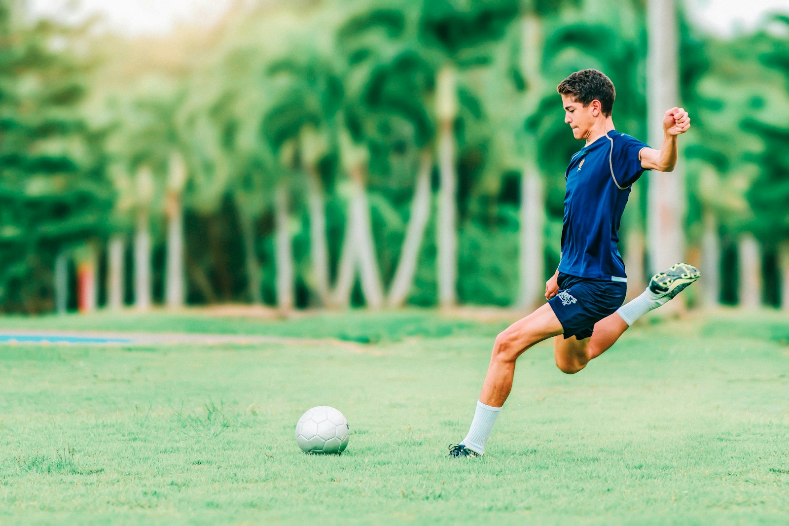 A soccer player kicking a ball on a grass field, used to illustrate the kind of player evaluation analytics that drives January transfer window decisions.
