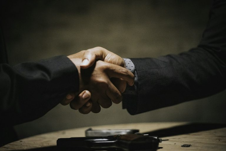 Two people shaking hands across a wooden table, used to illustrate WNBA second-half trade deadline negotiations.