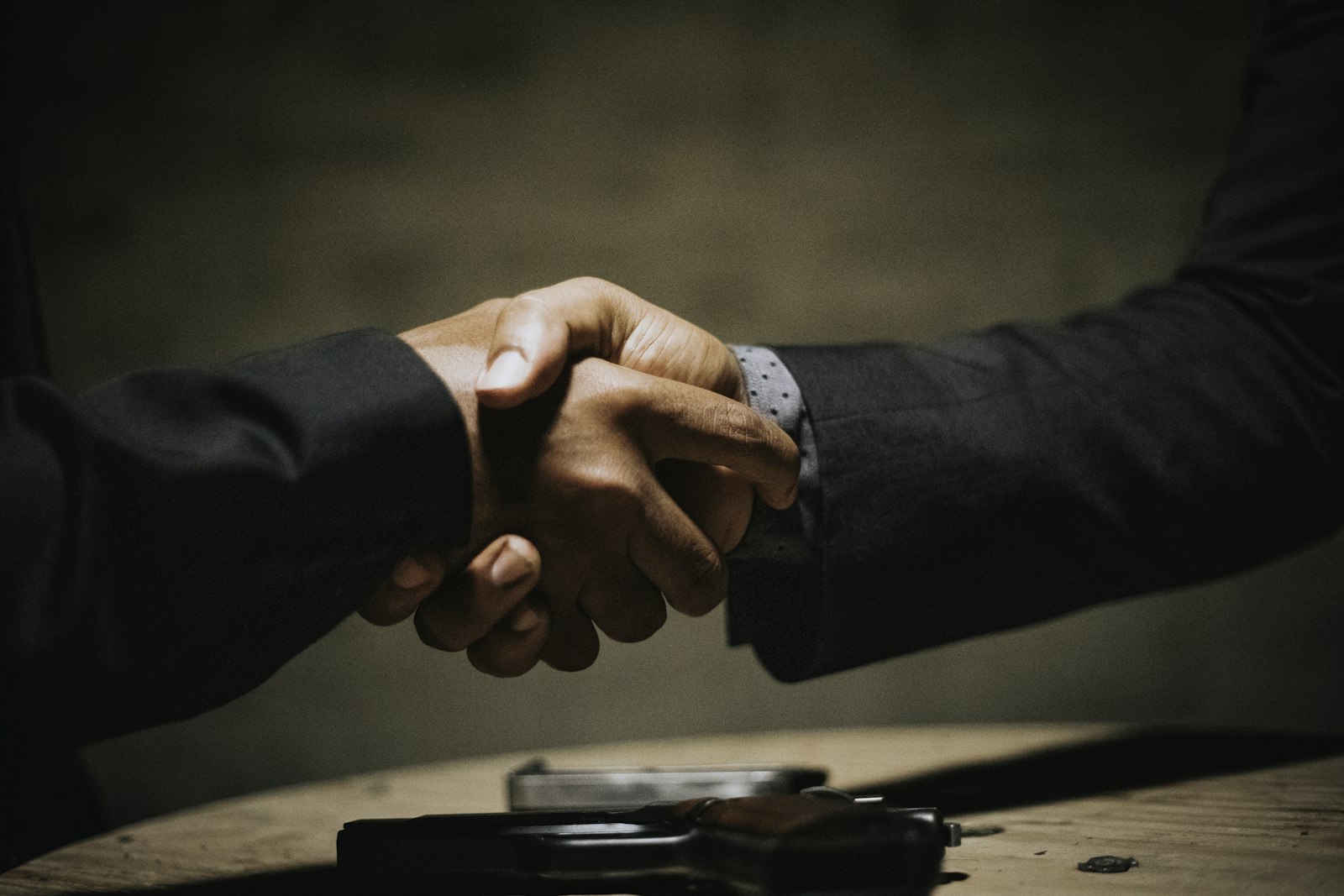 Two people shaking hands across a wooden table, used to illustrate WNBA second-half trade deadline negotiations.