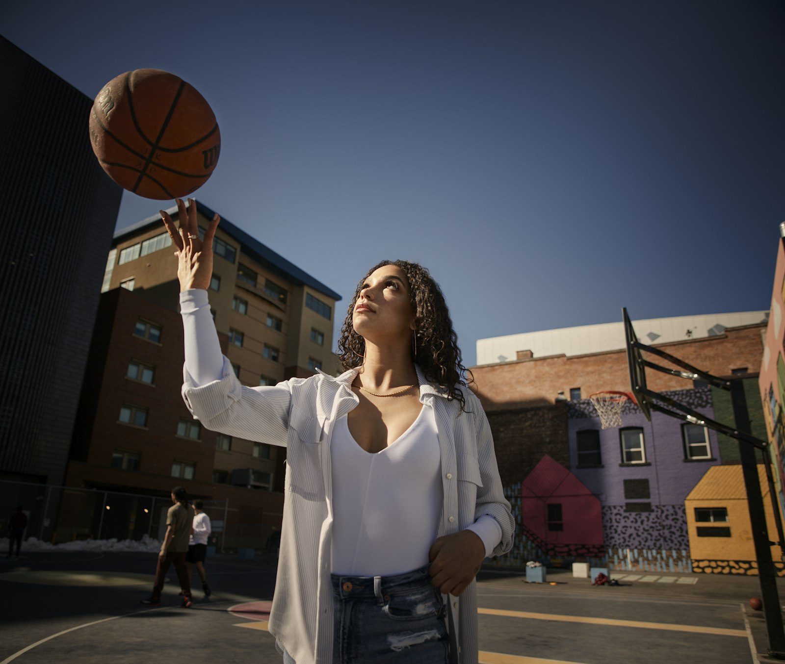 A woman in white long sleeves holding a basketball, used to illustrate the player-evaluation dimension of WNBA off-season roster construction.