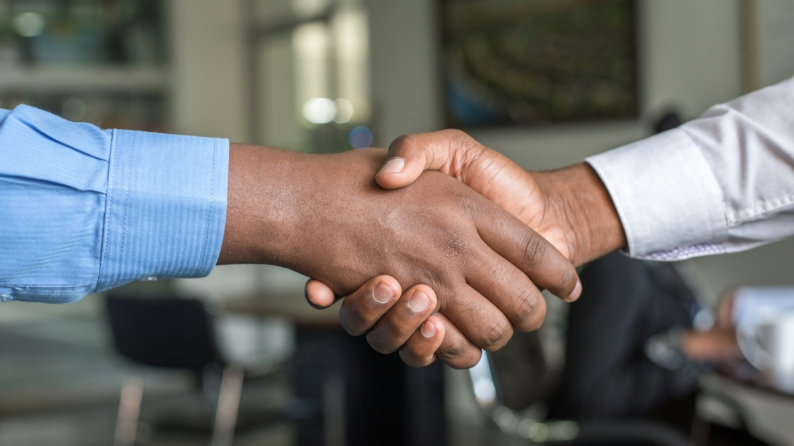 Close-up of two hands clasped in a firm handshake, representing the new editorial leadership at SportsHighLight
