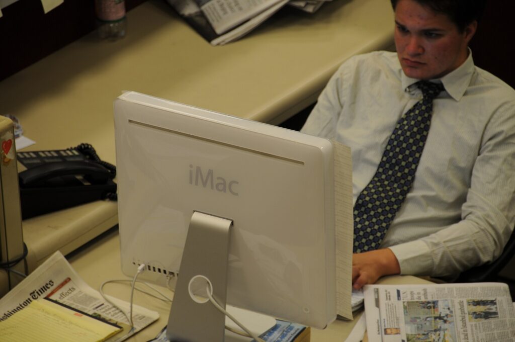 Desks and monitors in a newsroom with copy open on one of the screens