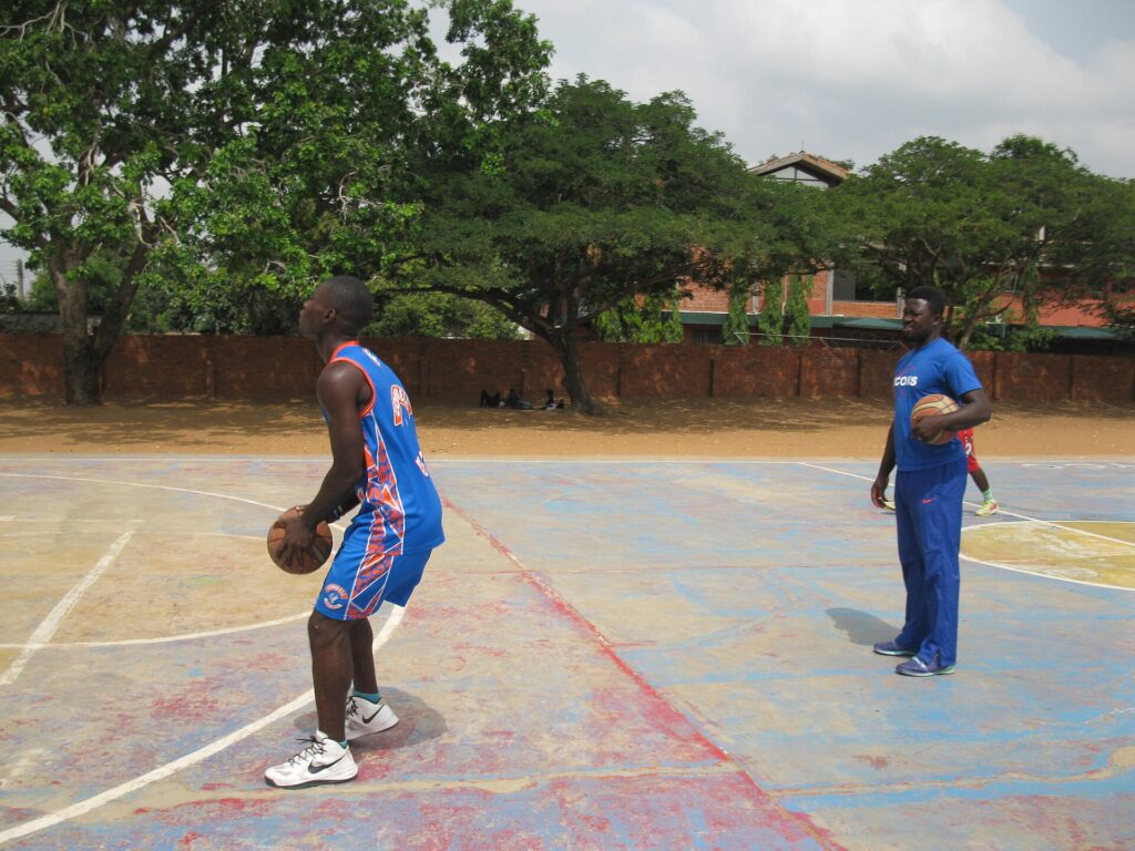A coach marking positions on a clipboard while players listen during a break in play