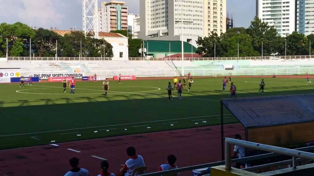 Players stretching cramped legs on the grass during a break before an additional period