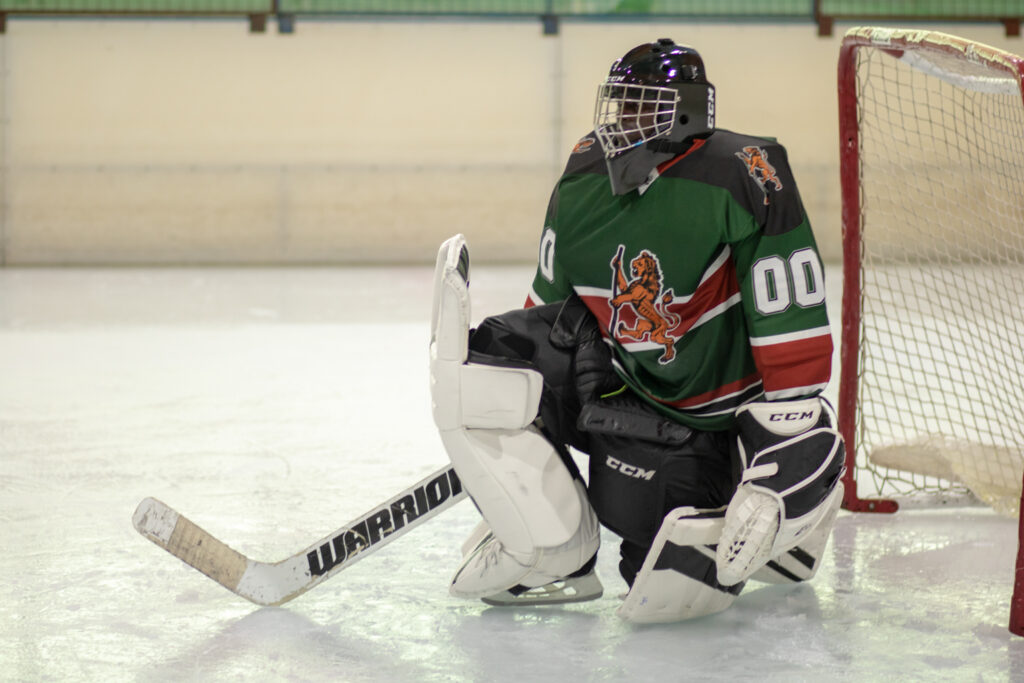A goaltender crouched in the crease facing a single attacker skating in alone