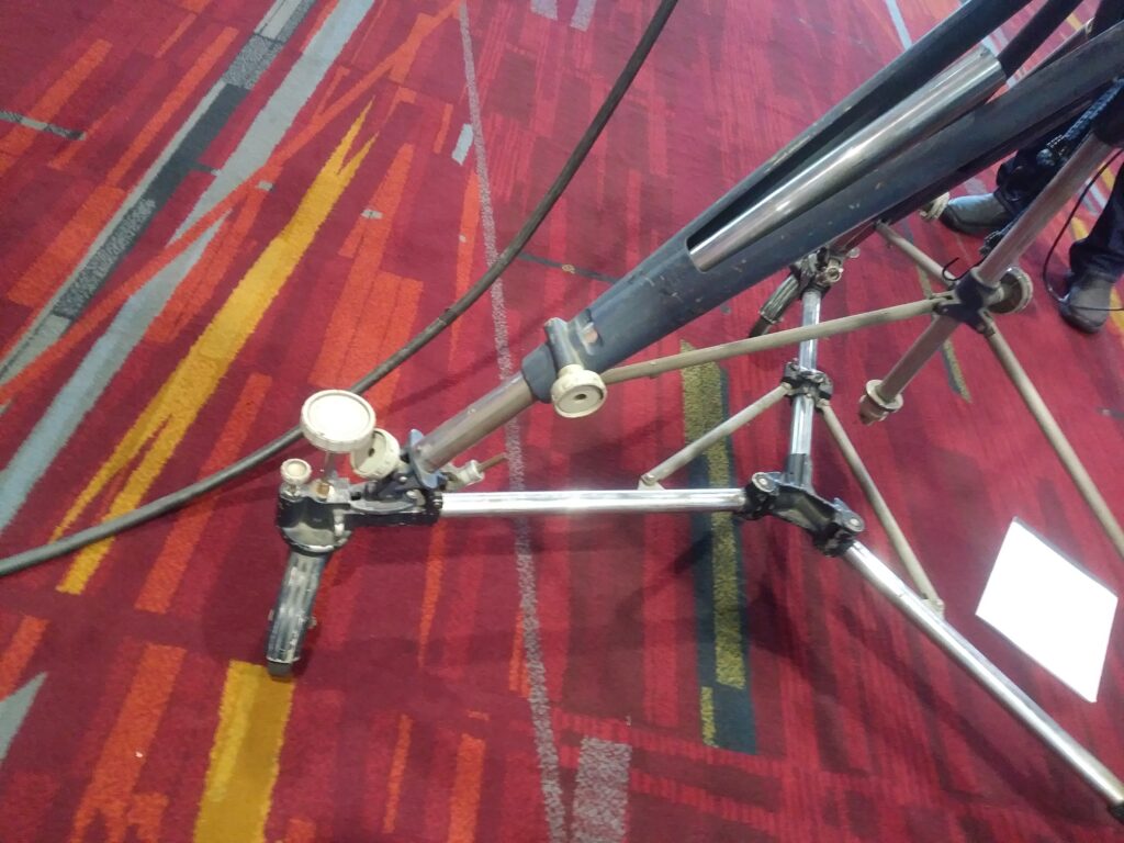 A camera mounted on a tripod pointed toward a playing field from the sideline