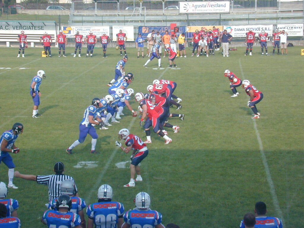 Two teams set either side of the ball moments before the snap on a marked field