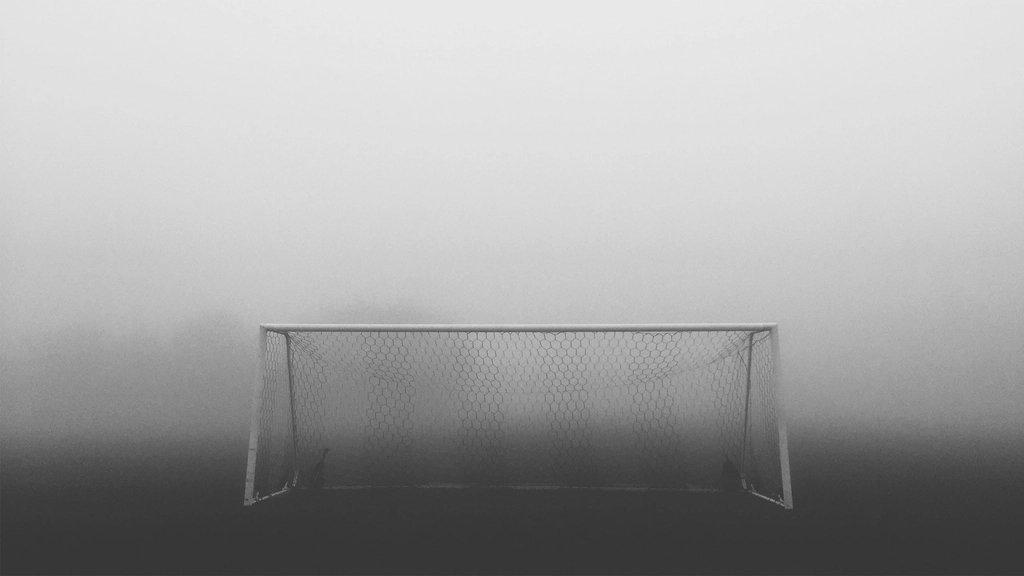 An empty goal seen from a sharp angle beside the byline with the net and posts in view