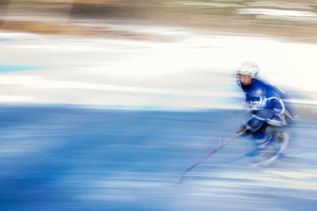 Two hockey forwards crossing the blue line together while a defenceman steps up to meet them