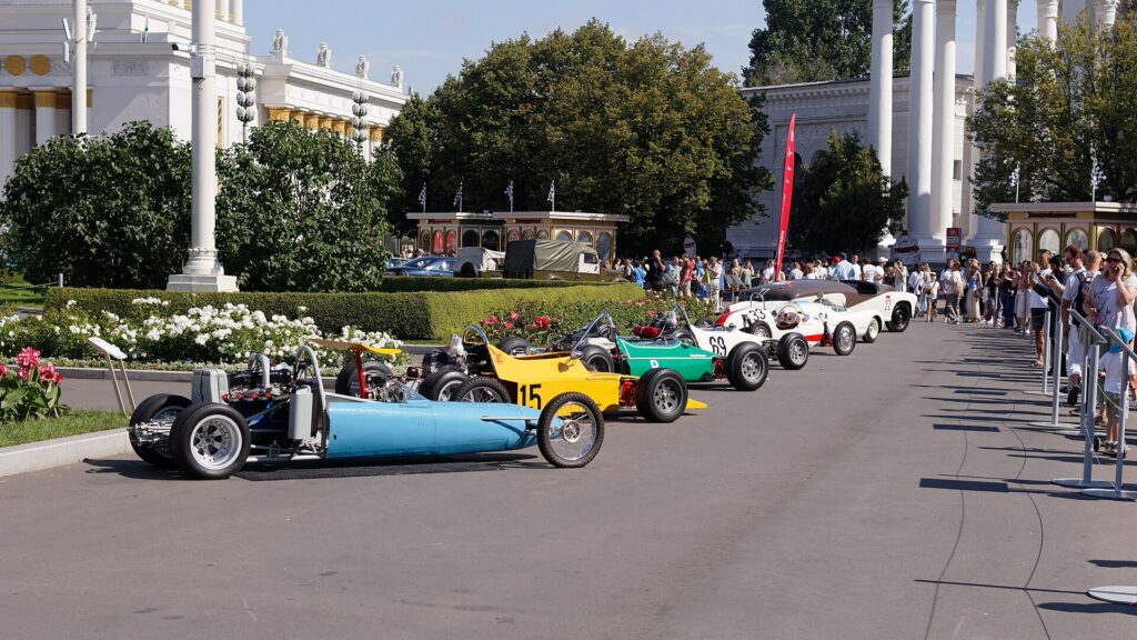 A tight pack of race cars bunched together approaching a restart on a racing circuit