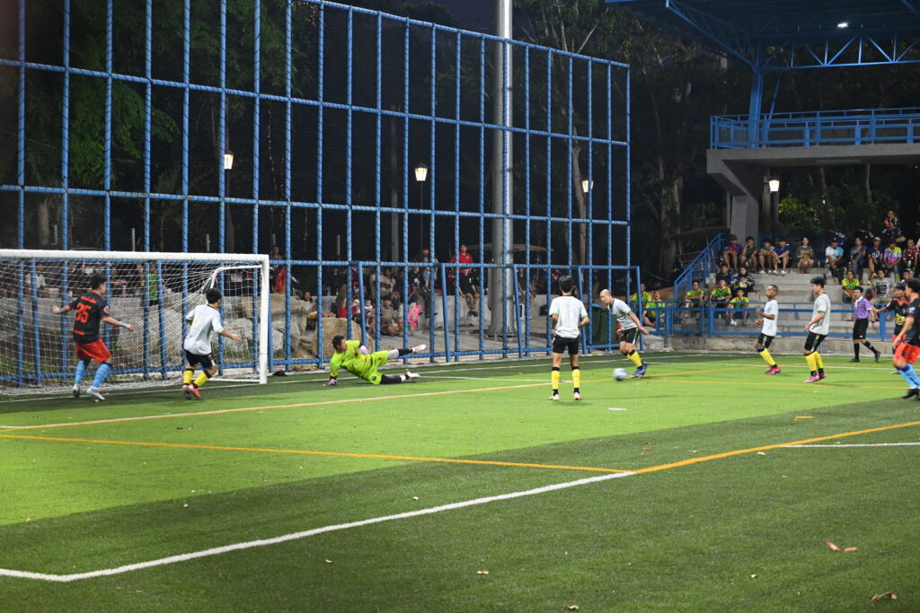 A forward striking the ball first time with a defender closing him down