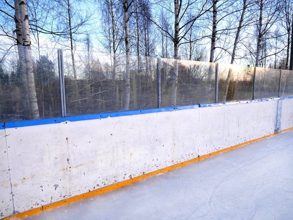 A corner of the rink with the boards and the goal line visible behind the net