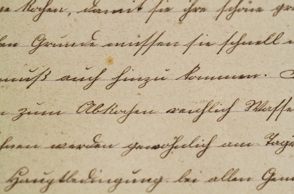 A handwritten letter placed on a wooden desk beside a pen and a cup of coffee