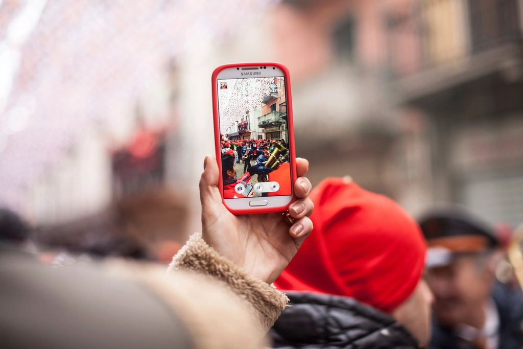 A hand holding a phone playing a video clip with a stadium visible on the screen