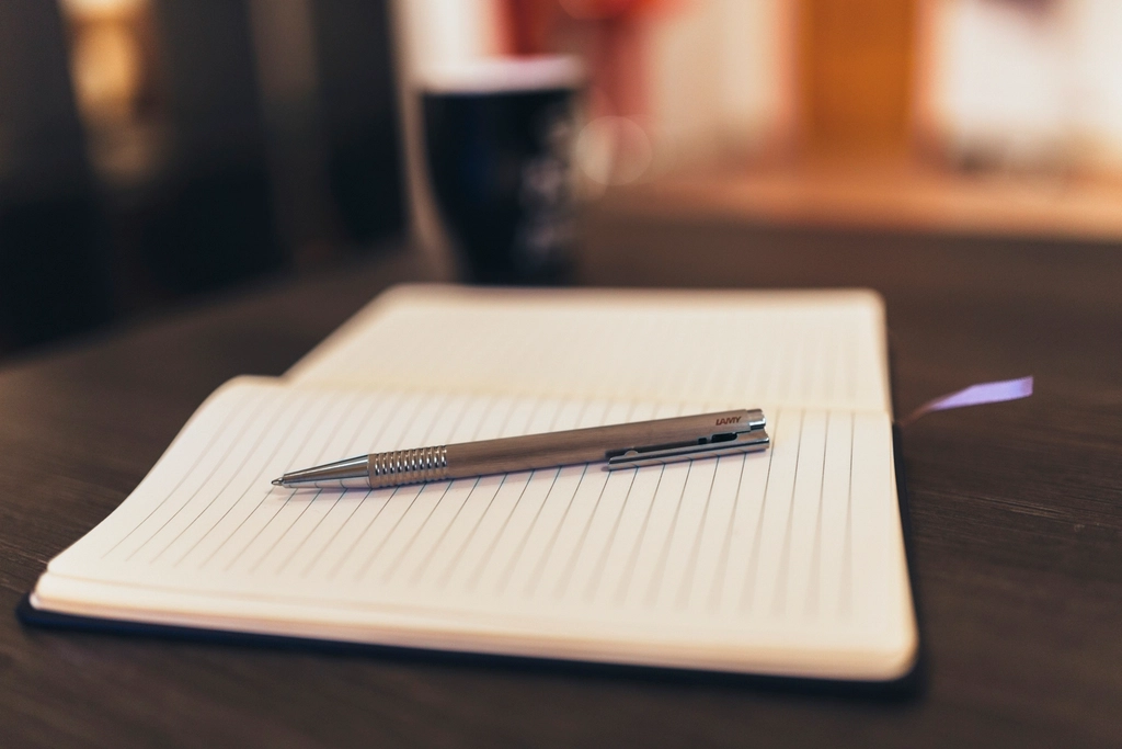 An open notebook and pen beside a screen showing a match in progress
